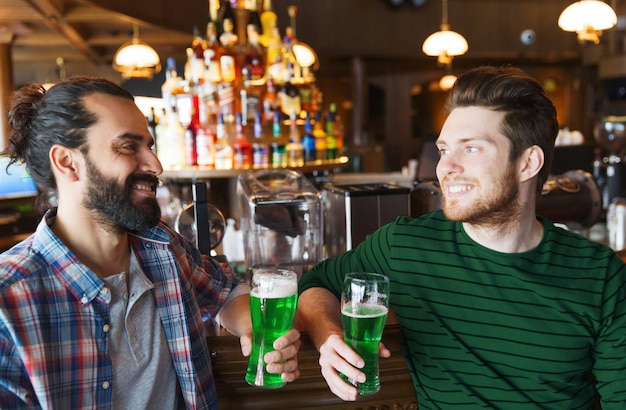 Photo people leisure and st patricks day concept happy male friends drinking green beer at bar or pub