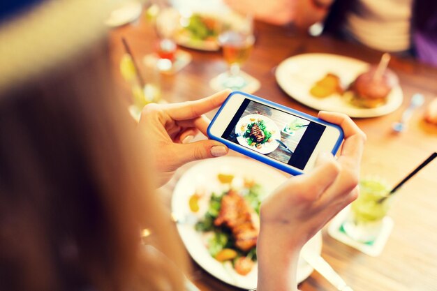 사람, 레저, 기술 및 인터넷 중독 개념 - 레스토랑에서 스마트폰으로 음식을 촬영하는 여성 가까이