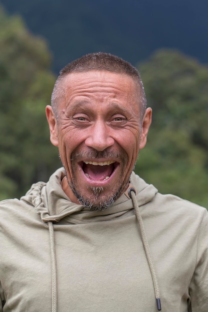 Concetto di persone e stile di vita felice uomo con la barba lunga di mezza età all'aperto su sfondo verde della natura primo piano del ritratto dell'uomo adulto