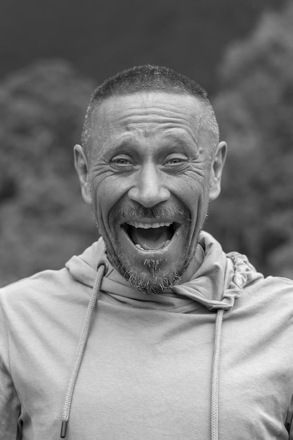 People and lifestyle concept. Middle-aged unshaven man outdoor against nature background, emotional portrait close up. Black and white