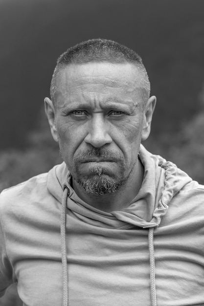 People and lifestyle concept Middleaged unshaven man outdoor against nature background emotional portrait closeup Black and white