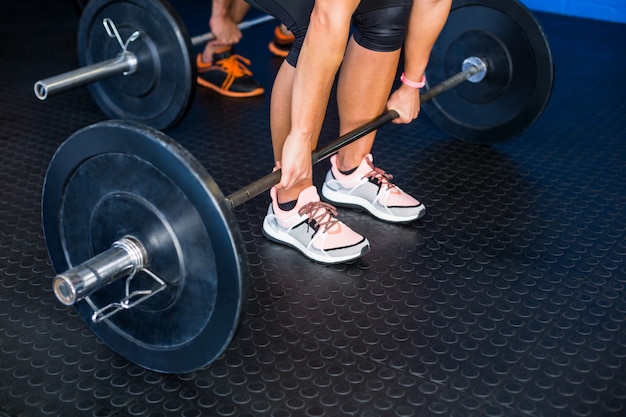 People lifting barbell at gym