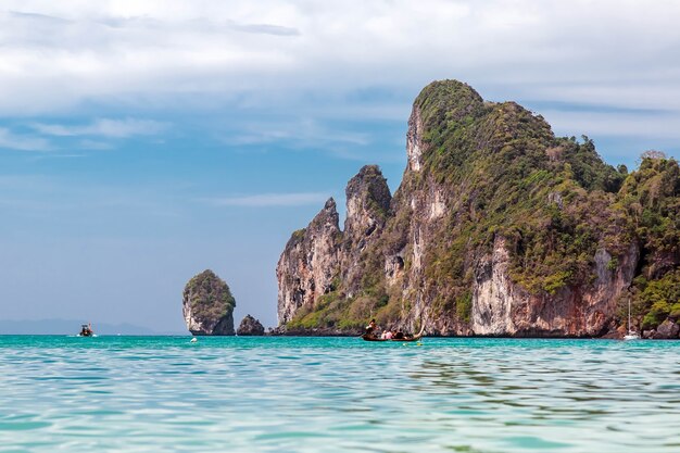 People on longtail motor boat sailing to water caves Mountain Phi Phi islandsView from water line