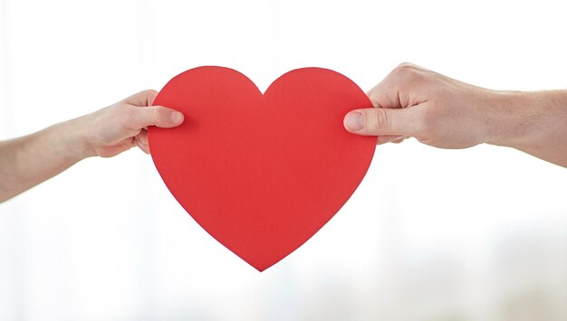 people, love, charity and family concept - close up of child and male hands holding red heart shape at home