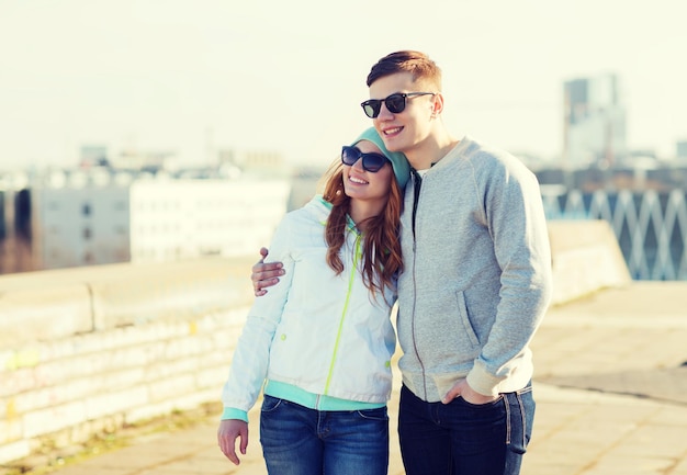 people, love and friendship concept - happy teenage couple walking in city