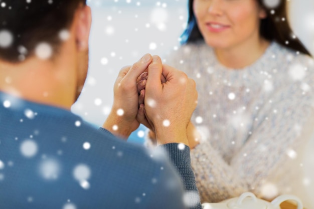 people, love, romance and dating concept - close up of couple drinking tea and holding hands at cafe or restaurant