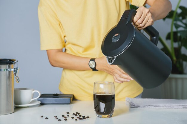 People make use kettle pouring hot water making iced coffee or\
cold americano coffee into the cup