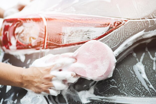 車を洗うためのピンクのスポンジを手を持つ人々 コンセプト洗車クリーン