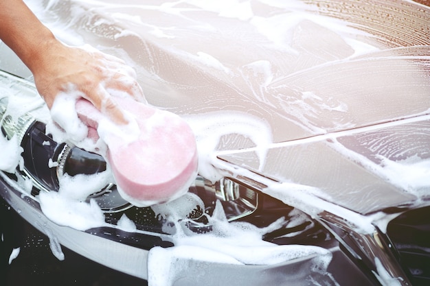 Persone uomo tenendo la mano rosa spugna per il lavaggio dell'auto. autolavaggio di concetto pulito.