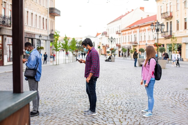 Люди в масках стоят в очереди, соблюдая социальную дистанцию