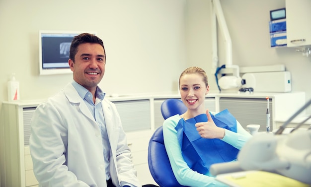 Photo people, medicine, stomatology and health care concept - happy male dentist with woman patient talking at dental clinic office