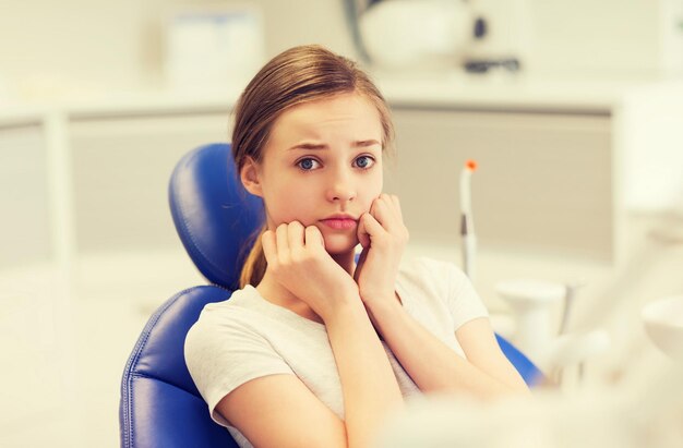 Photo people, medicine, stomatology and phobia concept - scared and terrified patient girl at dental clinic office