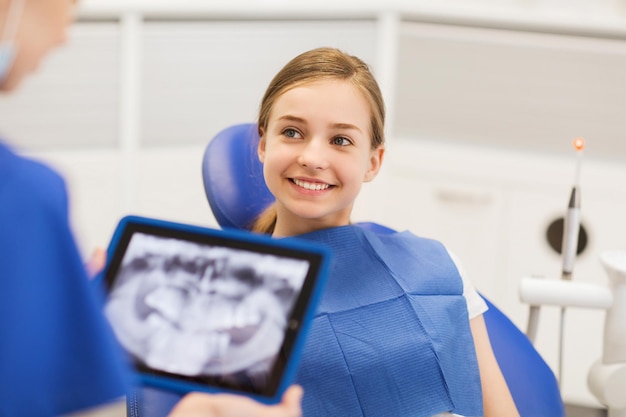 people, medicine, stomatology, technology and health care concept - dentist with x-ray on tablet pc computer and girl patient