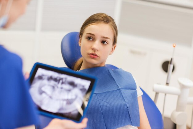 люди, медицина, стоматология, технология и концепция здравоохранения - дантист с рентгеном на планшетном компьютере и девушка-пациент