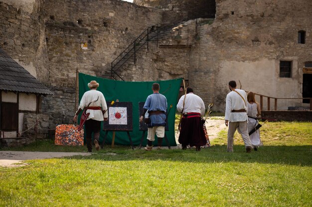 城の領土に弓を持った中世の服を着た人々