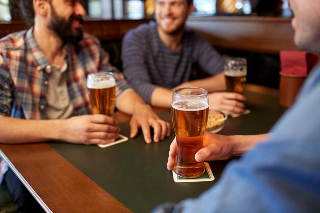 Photo people, men, leisure, friendship and communication concept - close up of happy male friends drinking draft beer at bar or pub