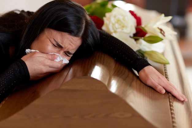 Foto persone e concetto di lutto - donna che piange con la bara al funerale in chiesa