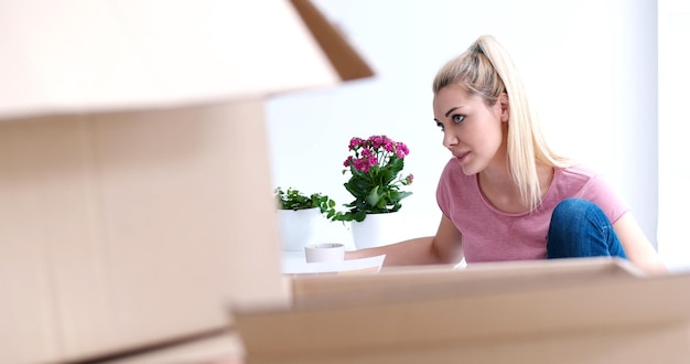 people, moving new place and repair concept   happy beautiful  young woman with many cardboard boxes sitting on floor with Cup at home