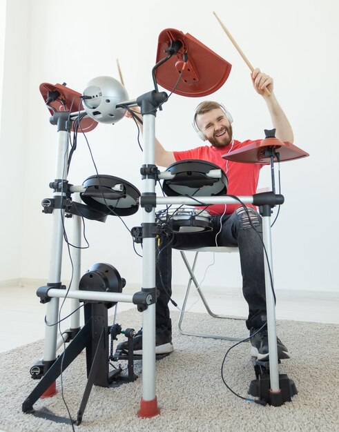 People, music and hobby concept - Tough man playing on electronic drum kit