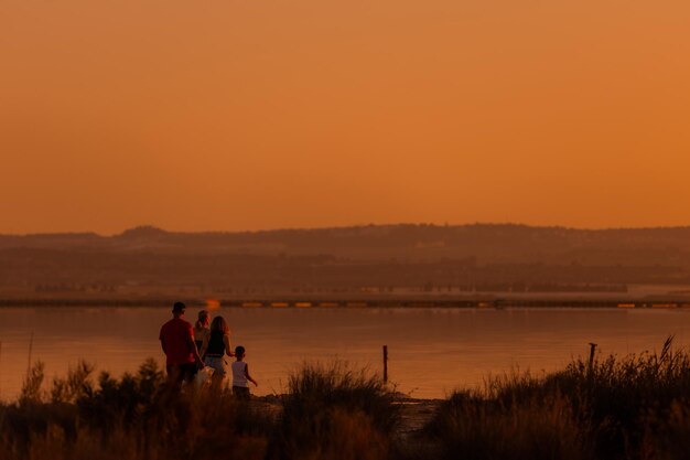 湖畔のオレンジ色の夕日の人々