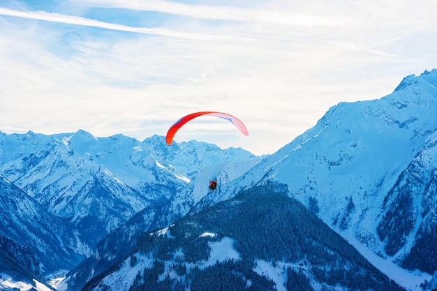 People paragliding on parachute in sky. Alps mountains on Penken Park ski resort in Tyrol in Mayrhofen in Zillertal valley in Austria in winter with snow. Austrian Alpine snowy slopes.