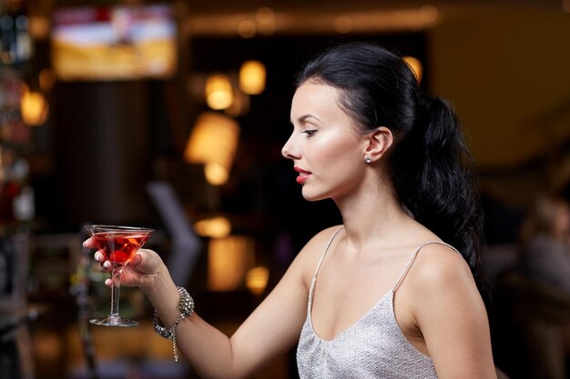 people, party, nightlife, drink and holidays concept - glamorous woman with cocktail at night club or bar