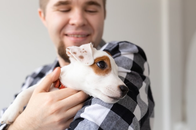 人、ペット、動物のコンセプト-ジャックラッセルテリアの子犬を保持している若い男のクローズアップ