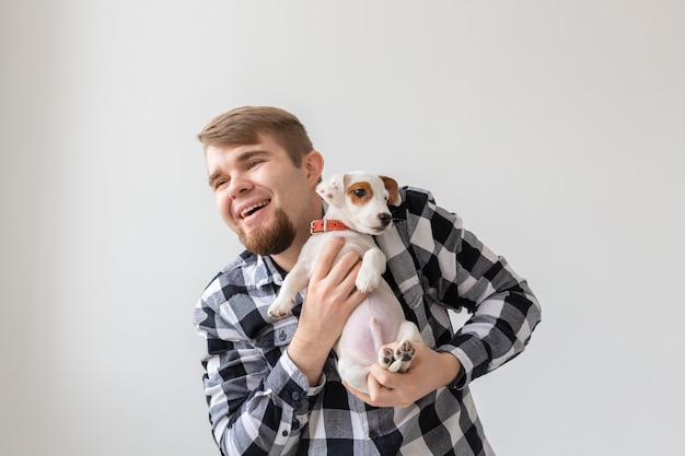 人、ペット、動物のコンセプト-ジャックラッセルテリアの子犬を保持しているハンサムな男。