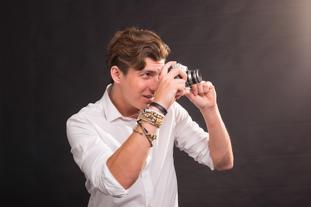 People, photographer and vintage concept - man searching for an interesting subject for his photo holding a vintage camera on brown surface