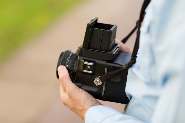 people, photography, technology, leisure and lifestyle - close up of male photographer with digital camera on city street