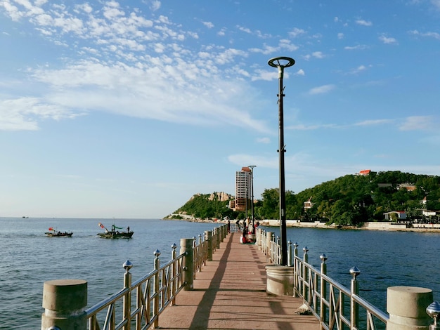 Люди на пирсе в море против неба