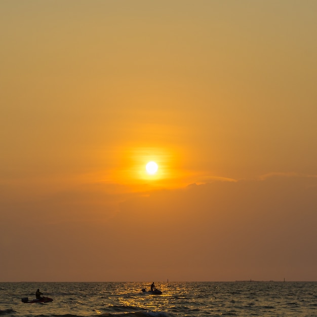 Persone che giocano a jet ski in mare con il tramonto