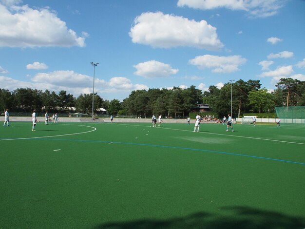 People playing soccer field against sky