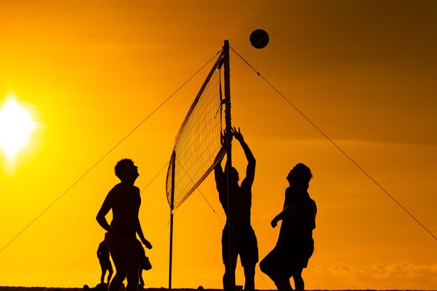 People playing volleyball at sunset