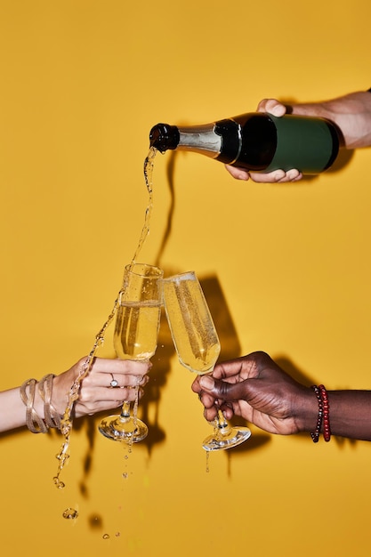 people pouring champagne with splashes against yellow background