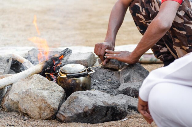 Photo people preparing food on campfire