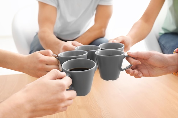 People putting cups of coffee together over wooden table Unity concept