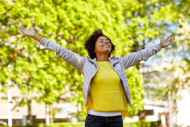 Photo people, race, ethnicity and portrait concept - happy african american young woman with open arms in summer park