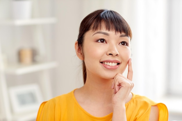 people, race, ethnicity and portrait concept - happy asian young dreaming woman or teenage girl face at home