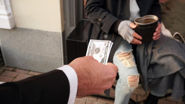 People reach out with money, dollars to a homeless person, a beggar to help, to give money for a donation