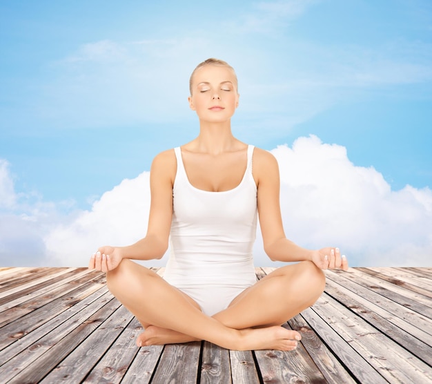 people, relaxation and health concept - woman in underwear meditating in yoga lotus pose