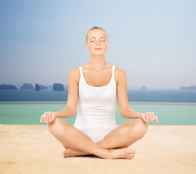 people, relaxation and health concept - woman in underwear meditating in yoga lotus pose