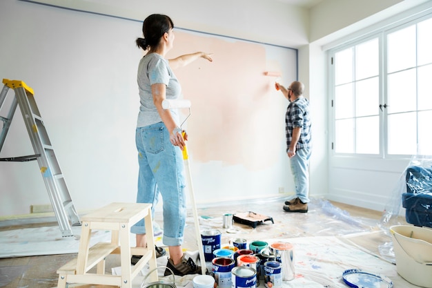 People renovating the house by painting the wall