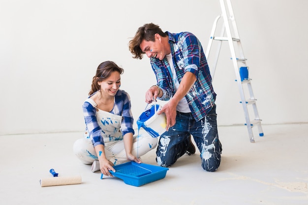 People, renovation and repair concept  portrait of happy couple pour paint