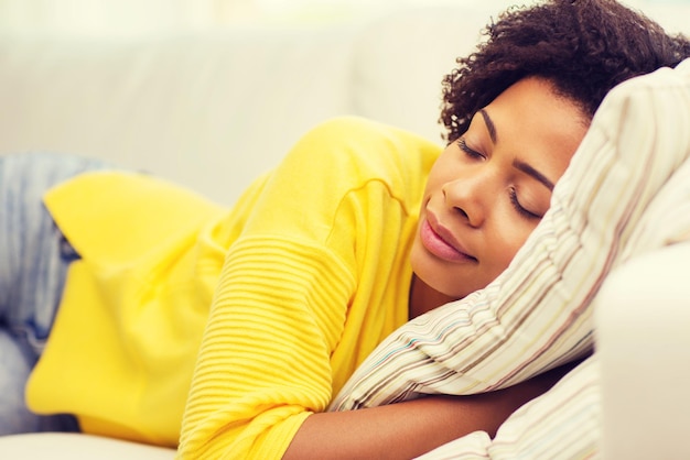 people, rest, comfort and leisure concept - african american young woman sleeping on sofa at home