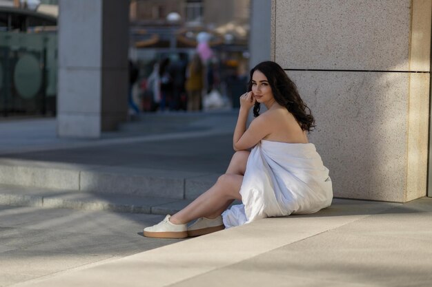 People rest comfort and leisure concept  Young woman through the evening streets wrapped in a blanket sitting on the steps of the mall