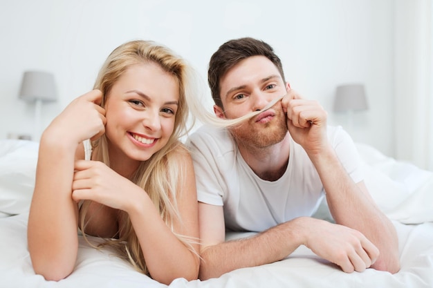 people, rest, love, relationships and happiness concept - happy couple lying in bed at home