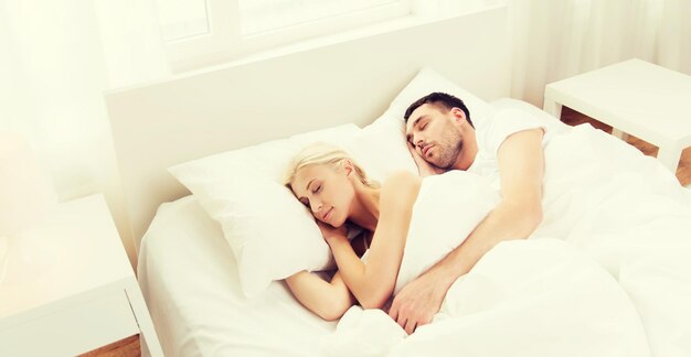 people, rest, relationships and happiness concept - happy couple sleeping in bed at home