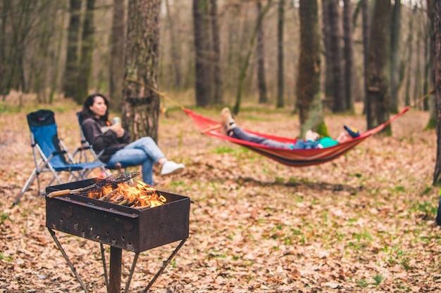 People resting outdoors grill with fire close up laying on hammock on background copy space