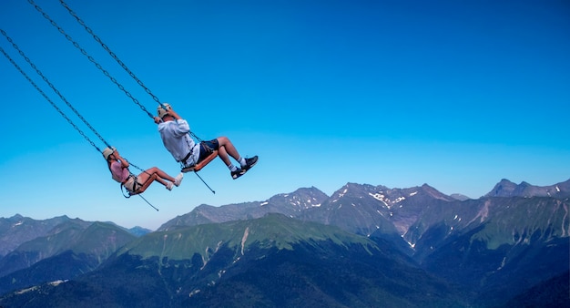 People ride on a swing over a precipice, extreme entertainment in the mountains